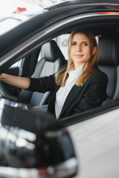 Piuttosto giovane donna alla guida della sua nuova auto (immagine dai toni di colore; DOF poco profondo)