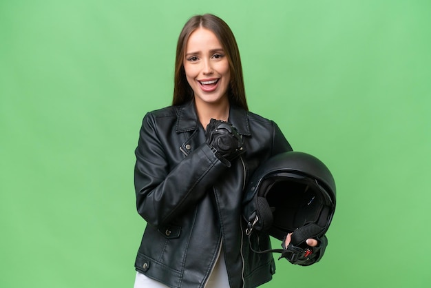 Piuttosto giovane donna caucasica con un casco da motociclista su sfondo isolato che celebra una vittoria