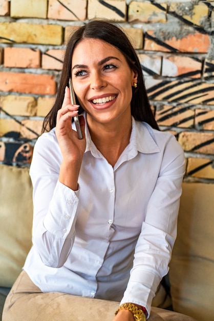 Piuttosto giovane donna che parla al cellulare nella caffetteria