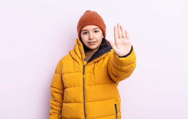 Piuttosto giovane donna che sembra seria mostrando palmo aperto facendo gesto di arresto concetto di tempo freddo