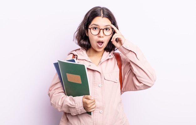 Piuttosto giovane donna che sembra sorpresa, realizzando un nuovo pensiero, idea o concetto. studente con il concetto di libri