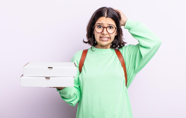 Piuttosto giovane donna che si sente stressata ansiosa o spaventata con le mani sulla testa da portare via il concetto