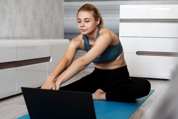 Piuttosto giovane donna in abiti sportivi guardando video online sul computer portatile