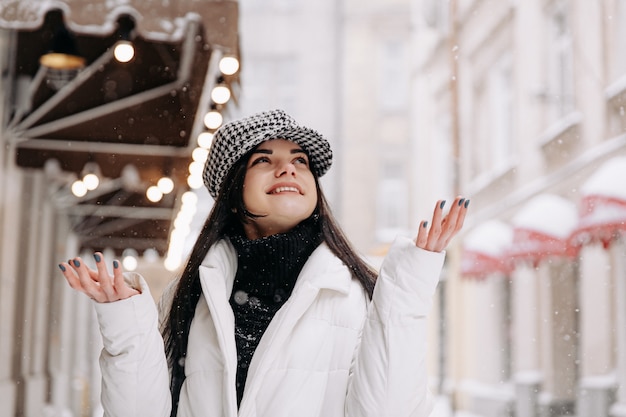 Piuttosto giovane donna in abito invernale che cammina durante la nevicata