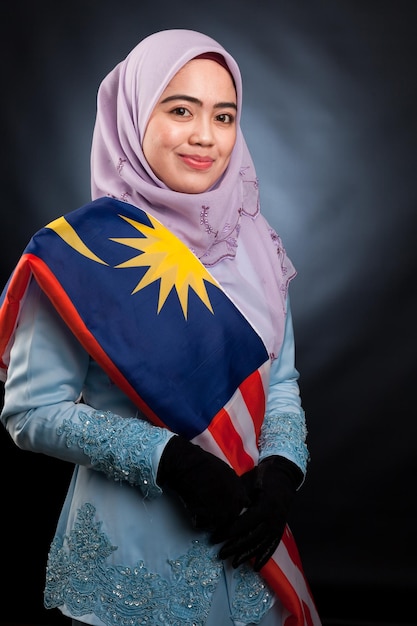 Piuttosto giovane donna musulmana asiatica possiede una bandiera della malesia bella in azione concetto di abbigliamento alla moda islamico