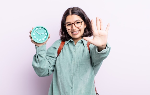 Piuttosto giovane donna sorridente e dall'aspetto amichevole, mostrando il numero cinque. concetto di sveglia