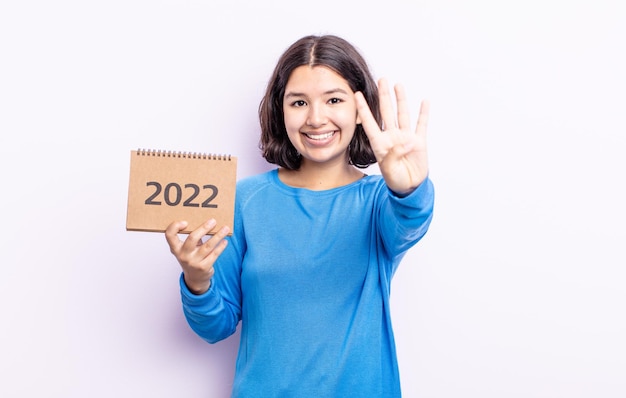 Piuttosto giovane donna sorridente e dall'aspetto amichevole, mostrando il numero quattro. Concetto di calendario 2022