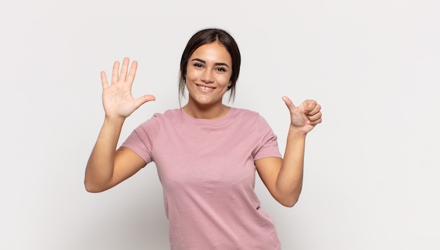 Piuttosto giovane donna sorridente e dall'aspetto amichevole, mostrando il numero sei