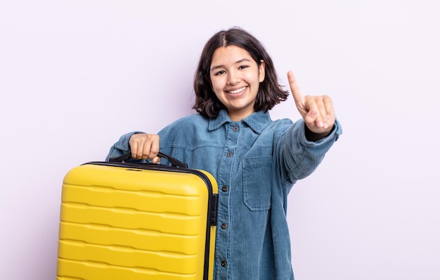 Piuttosto giovane donna sorridente e dall'aspetto amichevole, mostrando il numero uno. concetto di custodia da viaggio