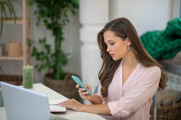 Piuttosto giovane imprenditrice seduto davanti al computer portatile mentre controlla i suoi messaggi