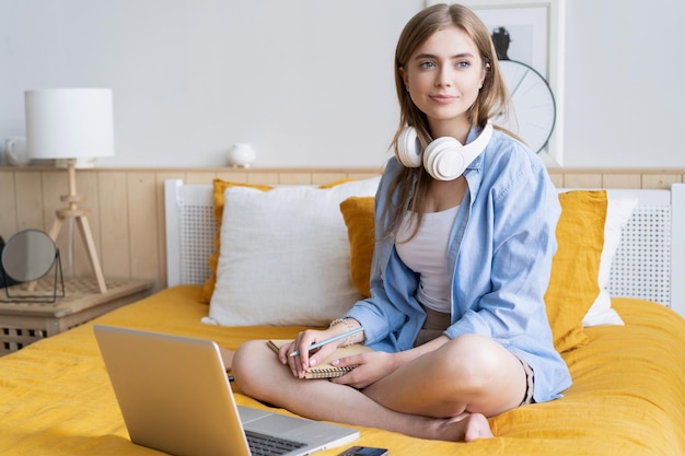 Piuttosto giovane studente che lavora a casa sul suo computer portatile seduto sul suo letto