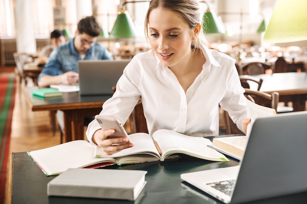 Piuttosto giovane studentessa intelligente che studia in biblioteca