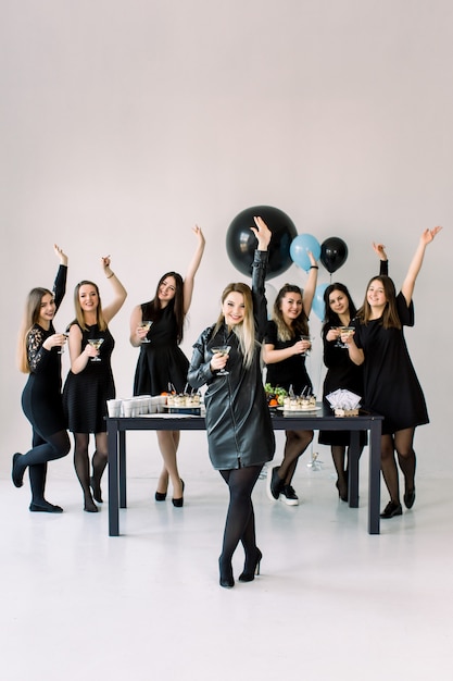 Piuttosto sette belle donne eleganti in elegante abito casual nero per festeggiare Capodanno, compleanno, divertirsi, ballare, bere cocktail alcolici