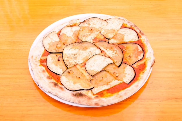 Pizza a fette di melanzane con tanto aglio e pomodoro fatta con farina di frumento su tavola di legno