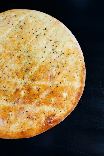 Pizza a fette su uno sfondo di pietra nera, vista dall'alto. Focaccia appena sfornata con formaggio