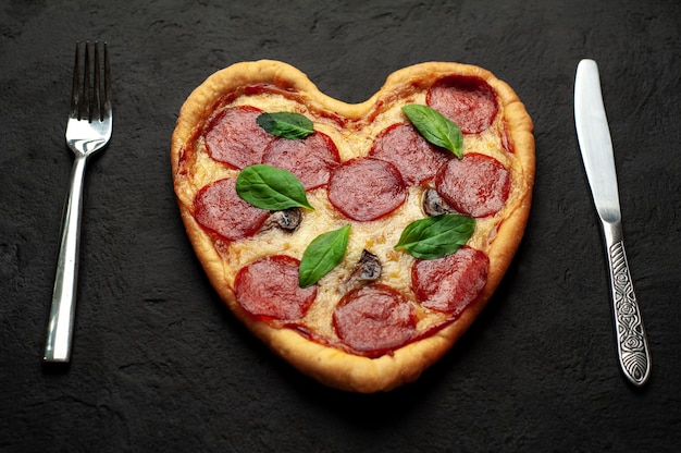 Pizza a forma di cuore su una pietra nera. Concetto romantico di amore di San Valentino