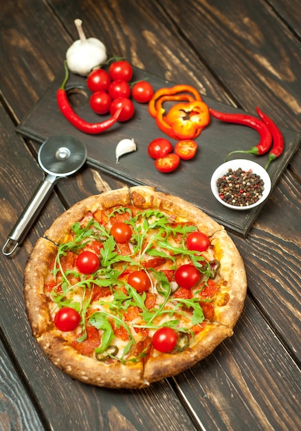 Pizza ai peperoni con ingredienti su fondo di legno