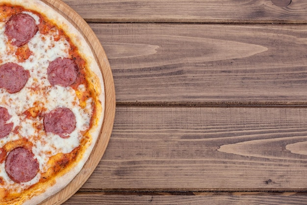 Pizza ai peperoni italiana con salame su fondo di legno scuro vista dall'alto Cibo tradizionale italiano Cibo di strada popolare