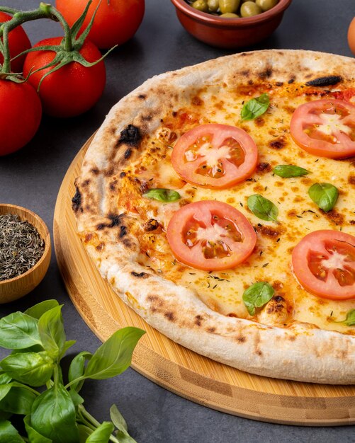 Pizza al formaggio con pomodori, uova, olio d'oliva e farina sul tavolo di legno