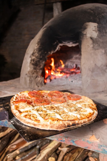 Pizza al pomodoro e quattro formaggi fresca di un forno paraguaiano in cemento (tatakua).