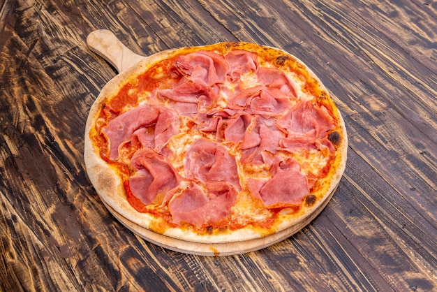 Pizza al prosciutto italiano con molto prosciutto e molta mozzarella fusa e pomodoro