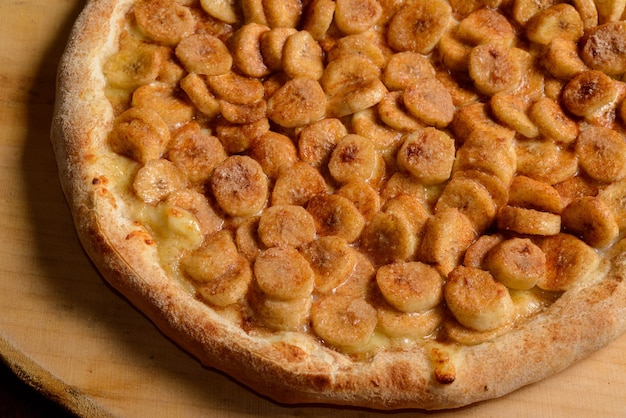 Pizza alla banana con zucchero e cannella su tavola di legno. Pizza dolce brasiliana.