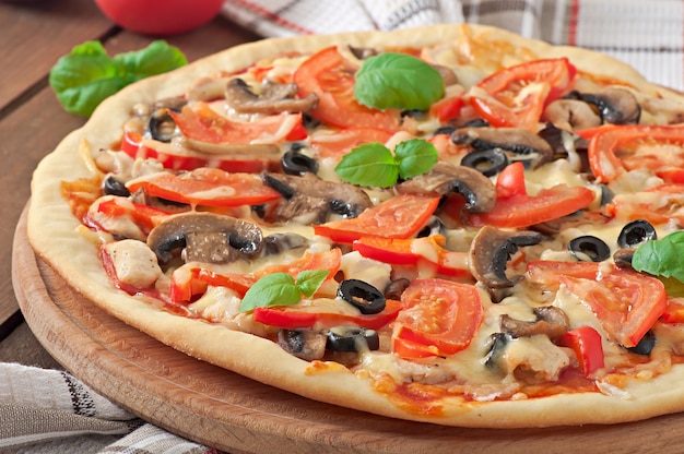 Pizza appetitosa con pollo, pomodori, peperoni e funghi