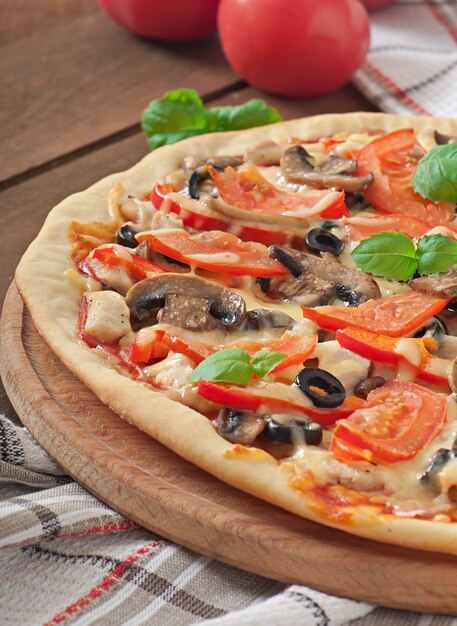 Pizza appetitosa con pollo, pomodori, peperoni e funghi