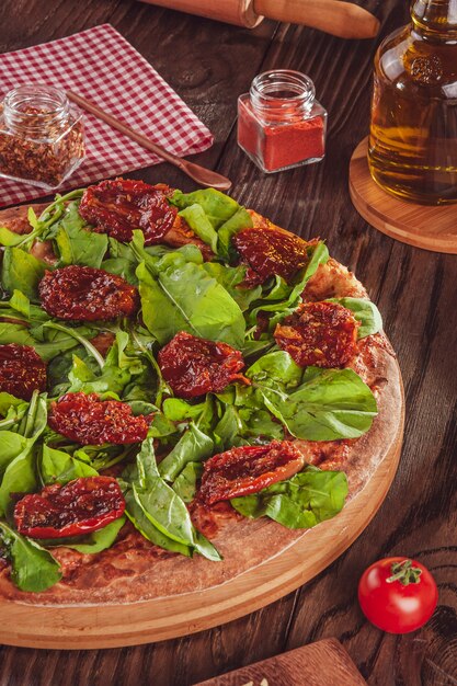 Pizza brasiliana con salsa di pomodoro, mozzarella, rucola, pomodori secchi e origano (Pizza de rucula con tomate seco) - Primo piano.