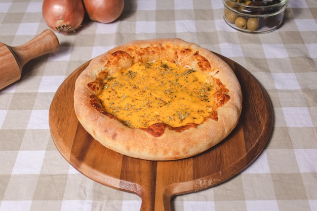 Pizza cheddar sopra un tavolo accanto agli accessori