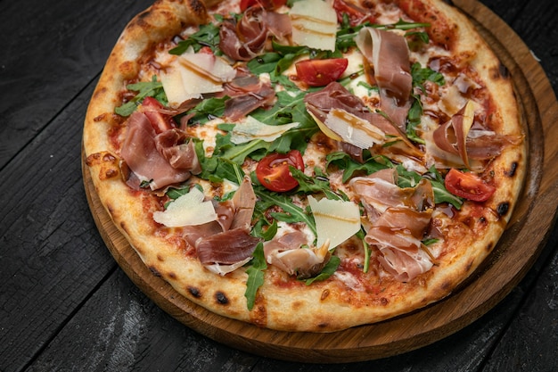 pizza con carne parmigiano e pomodori su una tavola di legno su un tavolo scuro