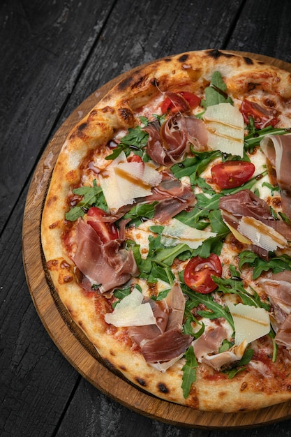 pizza con carne parmigiano e pomodori su una tavola di legno su un tavolo scuro