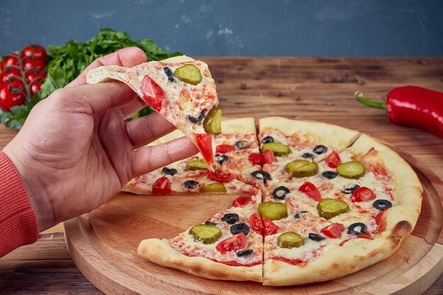 Pizza con carne, verdure e funghi, fondo in legno