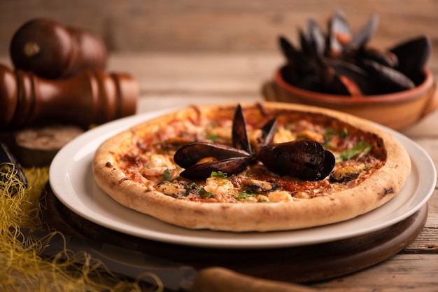 Pizza con cozze e gamberi su tavola di legno. sfondo di frutti di mare da vicino