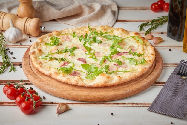 Pizza con fette, salsa ed erbe aromatiche, in legno bianco