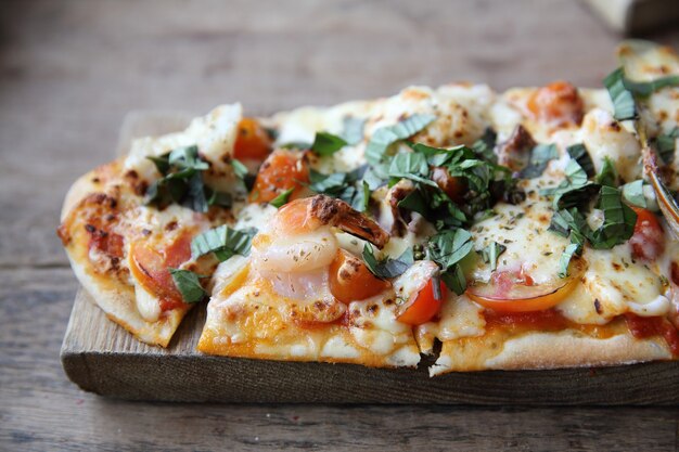 Pizza con frutti di mare e pomodori su un tavolo di legno, cibo italiano