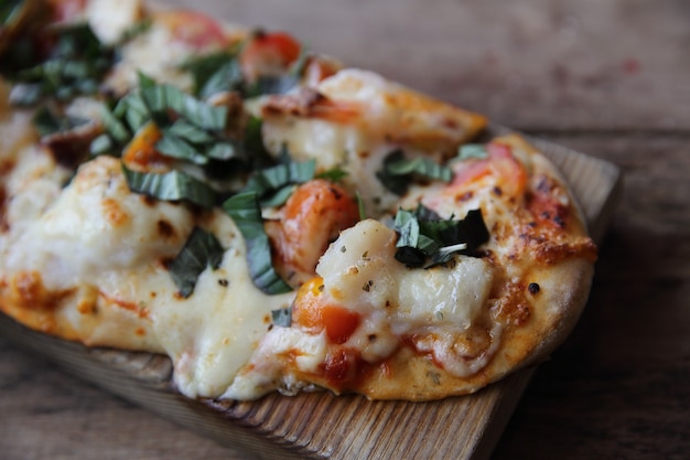 Pizza con frutti di mare e pomodori su un tavolo di legno, cibo italiano