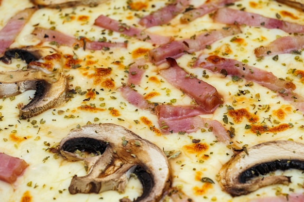 Pizza con funghi prosciutto formaggio e origano pizza al forno fresca closeup