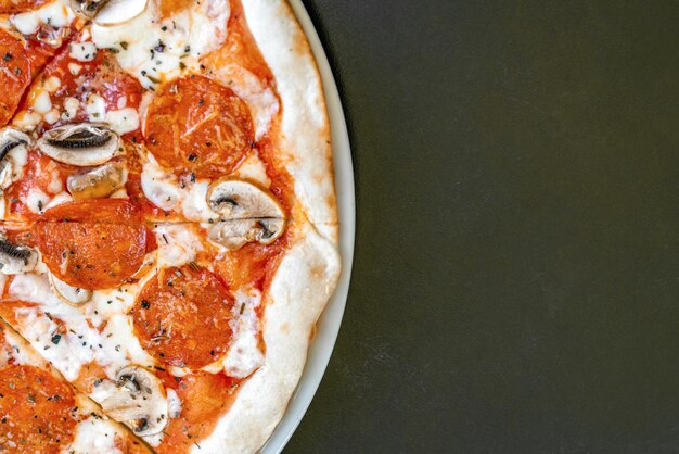 Pizza con mozzarella pomodori e funghi sul lato sinistro della vista dall'alto del telaio