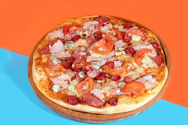 Pizza con pancetta formaggio ed erbe aromatiche su un piatto di legno con formaggio e pomodorini Su uno sfondo colorato