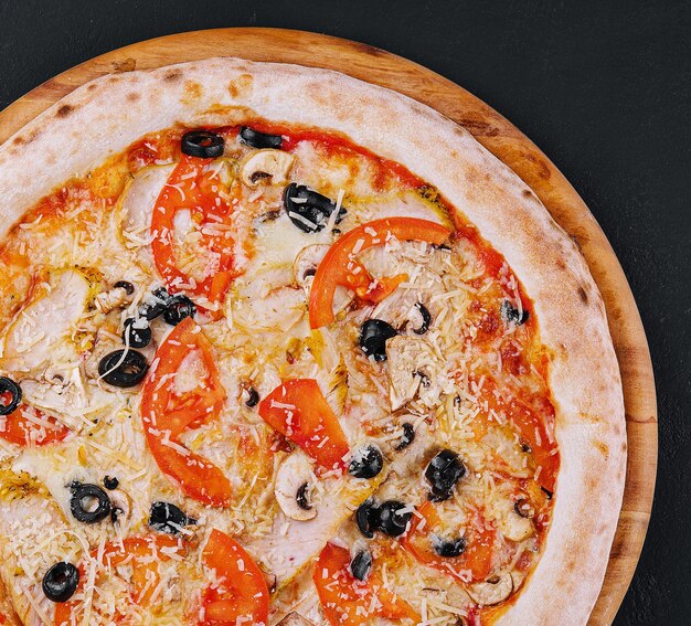 Pizza con pollo, pomodoro e funghi.