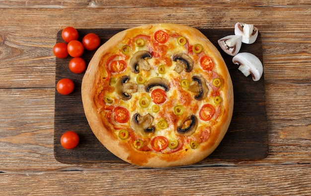 Pizza con pomodoro, mozzarella, salame e funghi su tavola di legno scuro