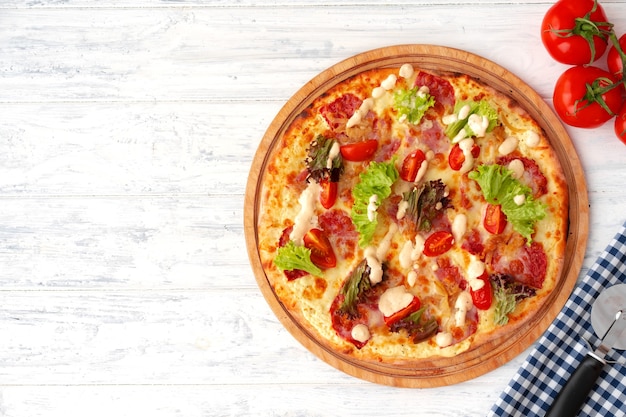 Pizza con prosciutto e insalata sul tavolo in legno vista dall'alto