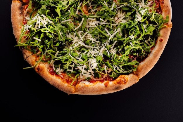 Pizza con rucola e parmigiano su fondo nero