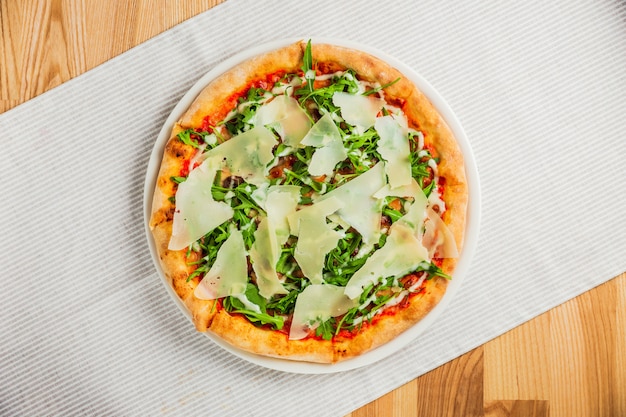 Pizza con rucola o rucola e parmigiano su un piatto bianco, vista dall'alto