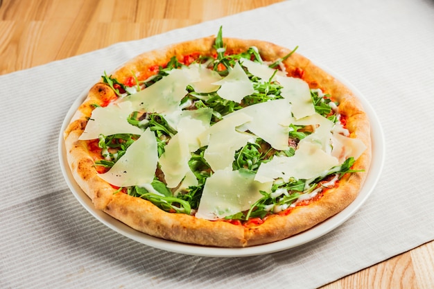 Pizza con rucola o rucola e parmigiano su un piatto bianco