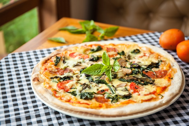 Pizza con salame, spinaci e pomodoro