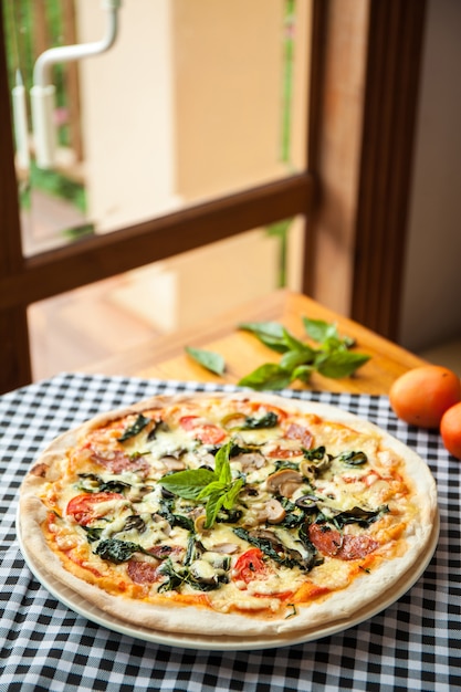 Pizza con salame, spinaci e pomodoro