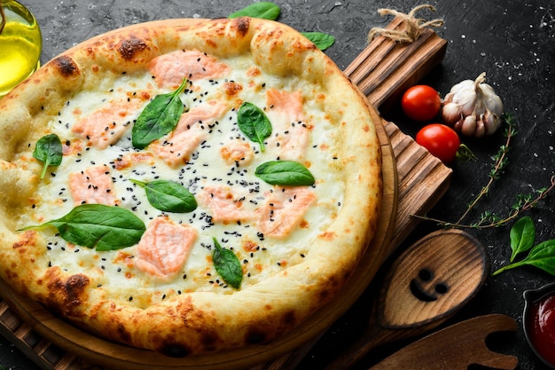 Pizza con salmone e pizza classica agli spinaci Su sfondo in pietra nera Vista dall'alto