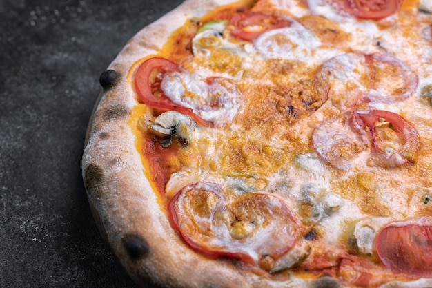 Pizza con verdure, funghi e formaggio, su un tavolo scuro